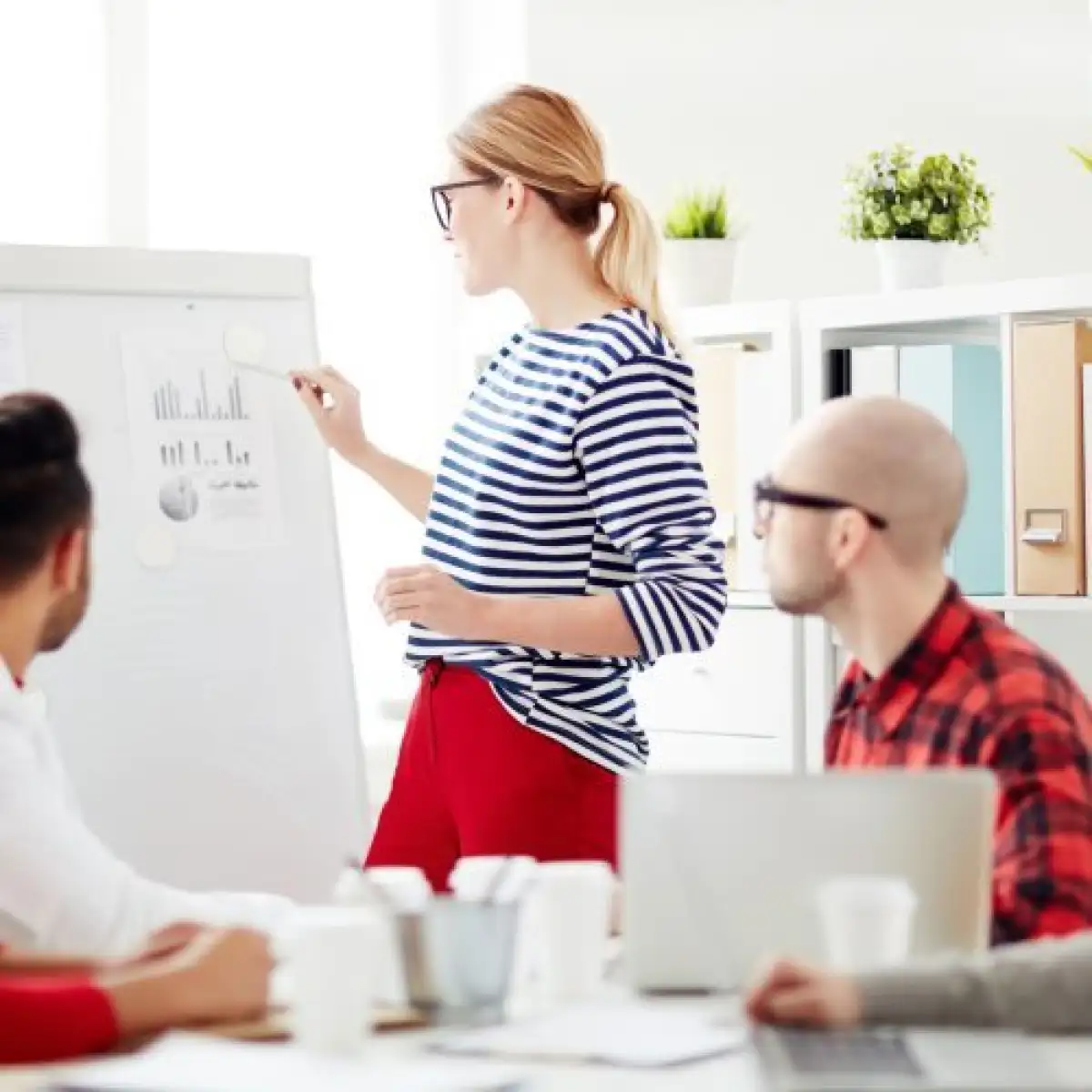 Personne qui présente au tableau aux personnes autour d'une table