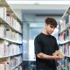Étudiant qui prend un livre dans une allée de la bibliothèque