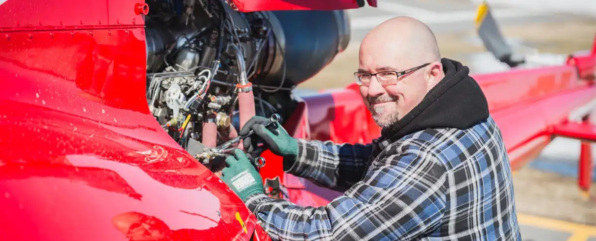 Un homme souriant qui travaille sur un moteur d'aéronef