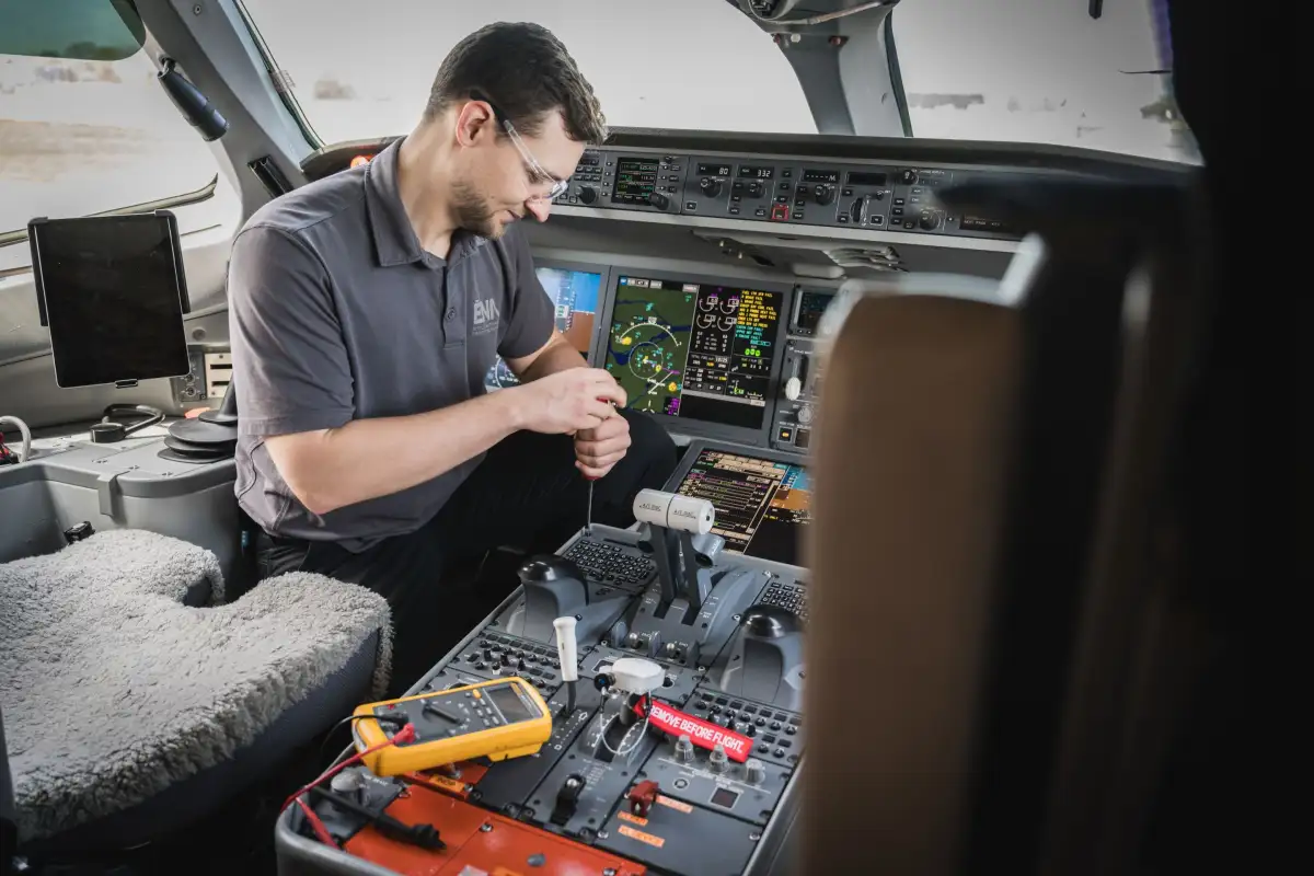 Étudiant retirant un composant dans un cockpit d'avion