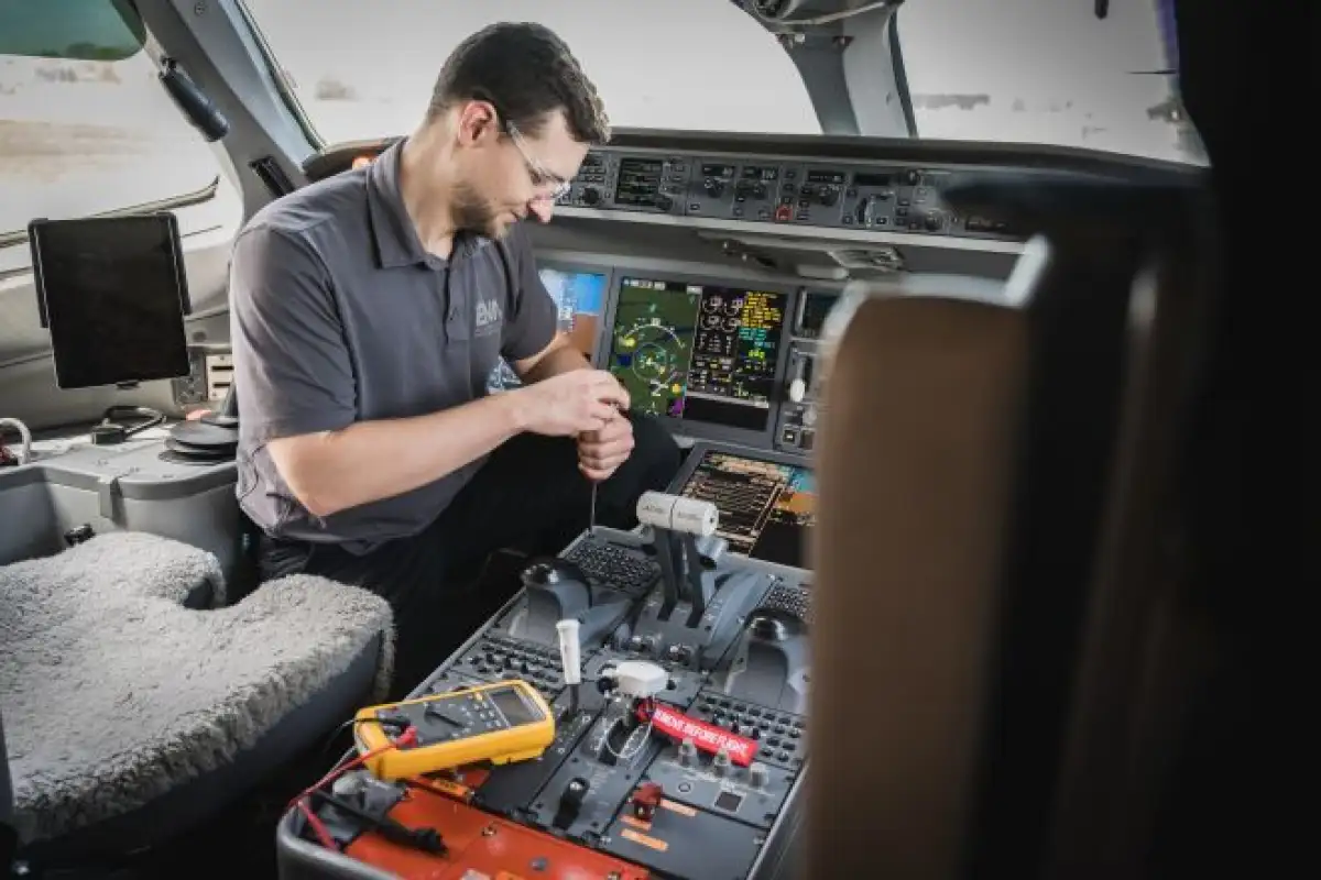 Étudiant retirant un composant dans un cockpit d'avion