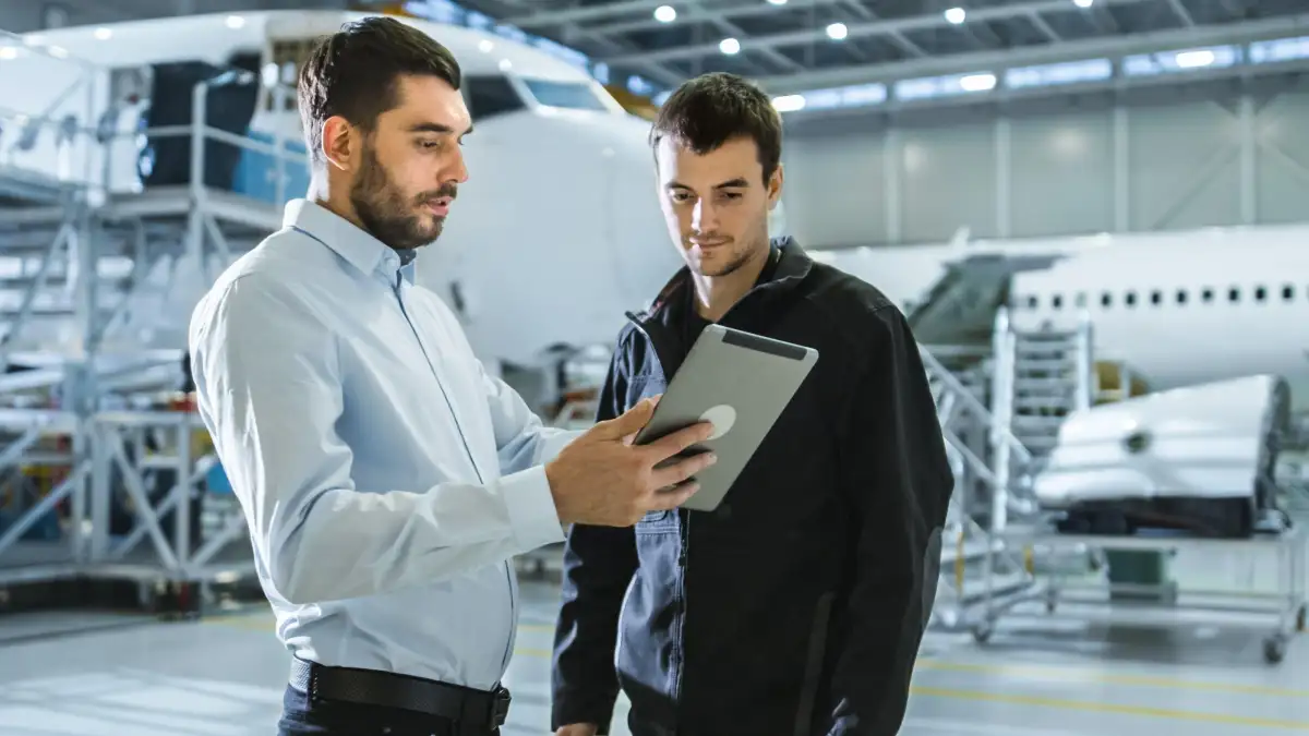 Deux personnes dans un hangar d'avion qui regardent une tablette