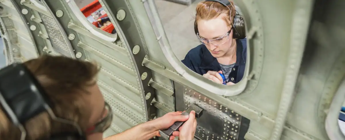 Une femme qui travaille manuellement sur la porte d'un avion