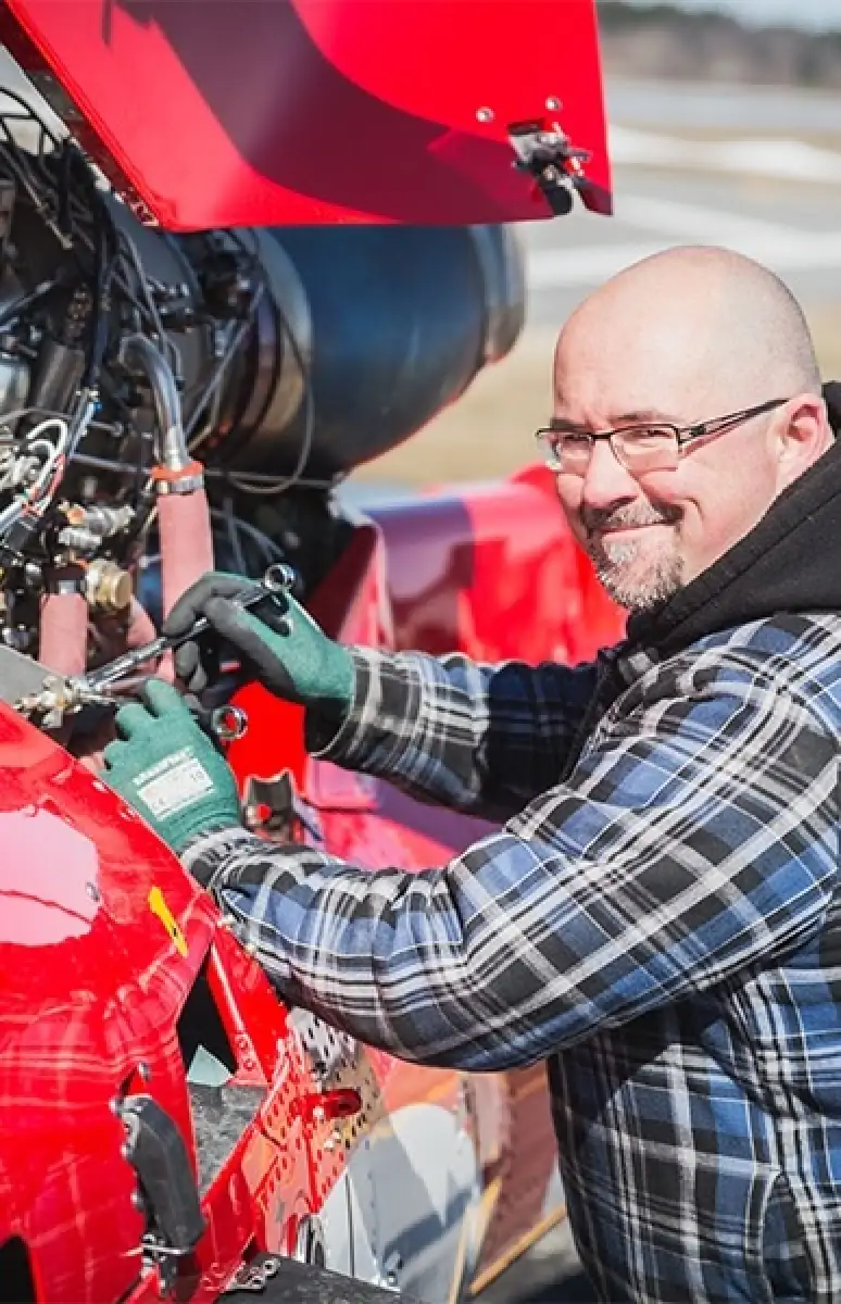 Personne souriante qui travaille sur un moteur d'avion