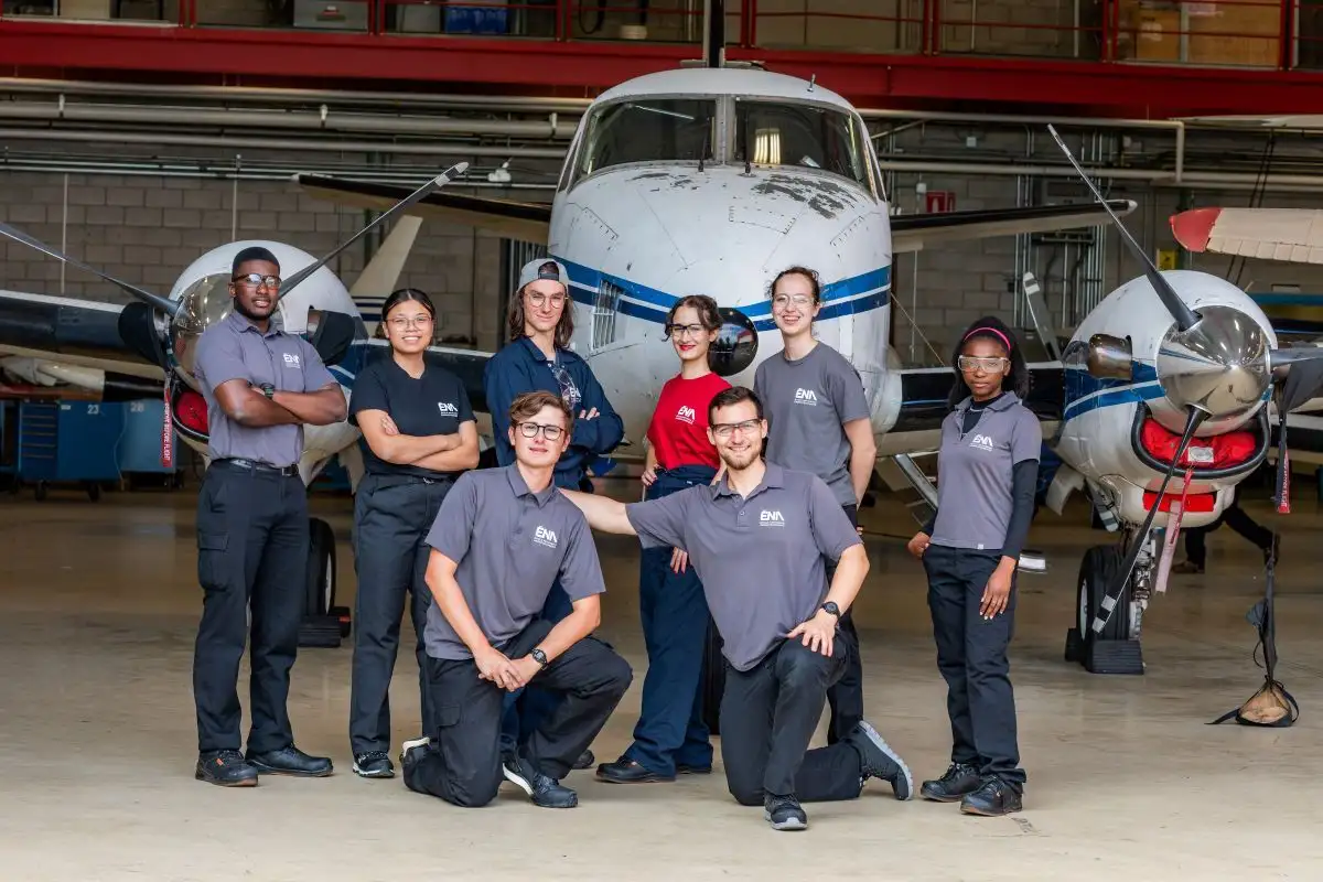 Groupe d'étudiant(e)s devant un avion dans un hangar