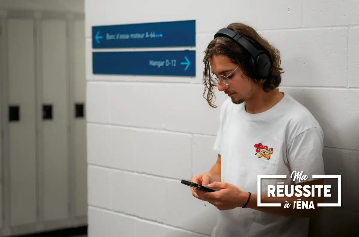 Personne étudiante adossée au mur d'un corridor