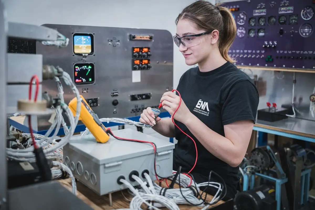 Etudiante inspectant un module avionique dans un atelier