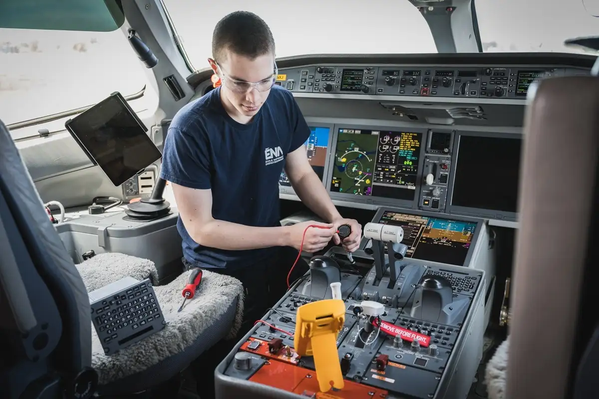 Etudiant inspectant un composant dans un poste de pilotage