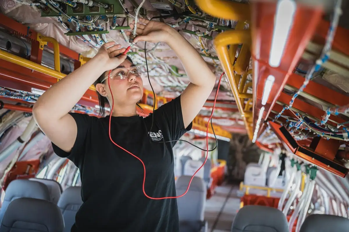 Etudiante inspectant un circuit électrique dans un avion