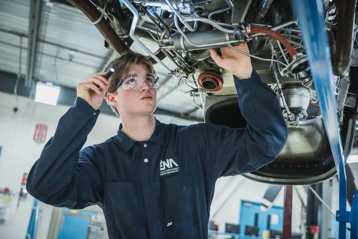 Etudiant inspectant un moteur d'avion