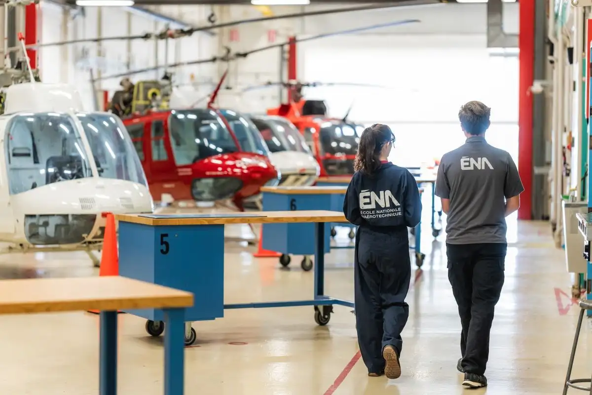 Etudiant et etudiante marchant dans le hangar d'hélicoptères